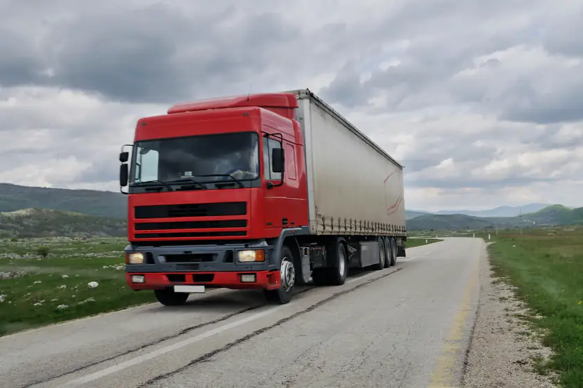 A curtainsider trailer on a rural main road